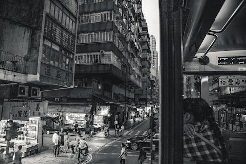 Yüksek Binaların Yakınında Yürüyen İnsanların Gri Tonlamalı Fotoğrafı