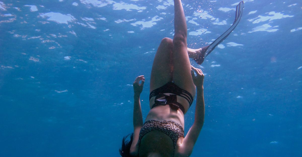 Rüyada Denizde Yüzmek - Rüya Tabiri ve Anlamı - Graceful woman freediving underwater, surrounded by clear blue ocean water.