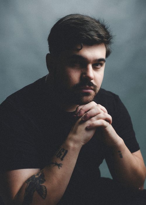 Free Dramatic portrait of a man with tattoo contemplating deeply in soft lighting. Stock Photo