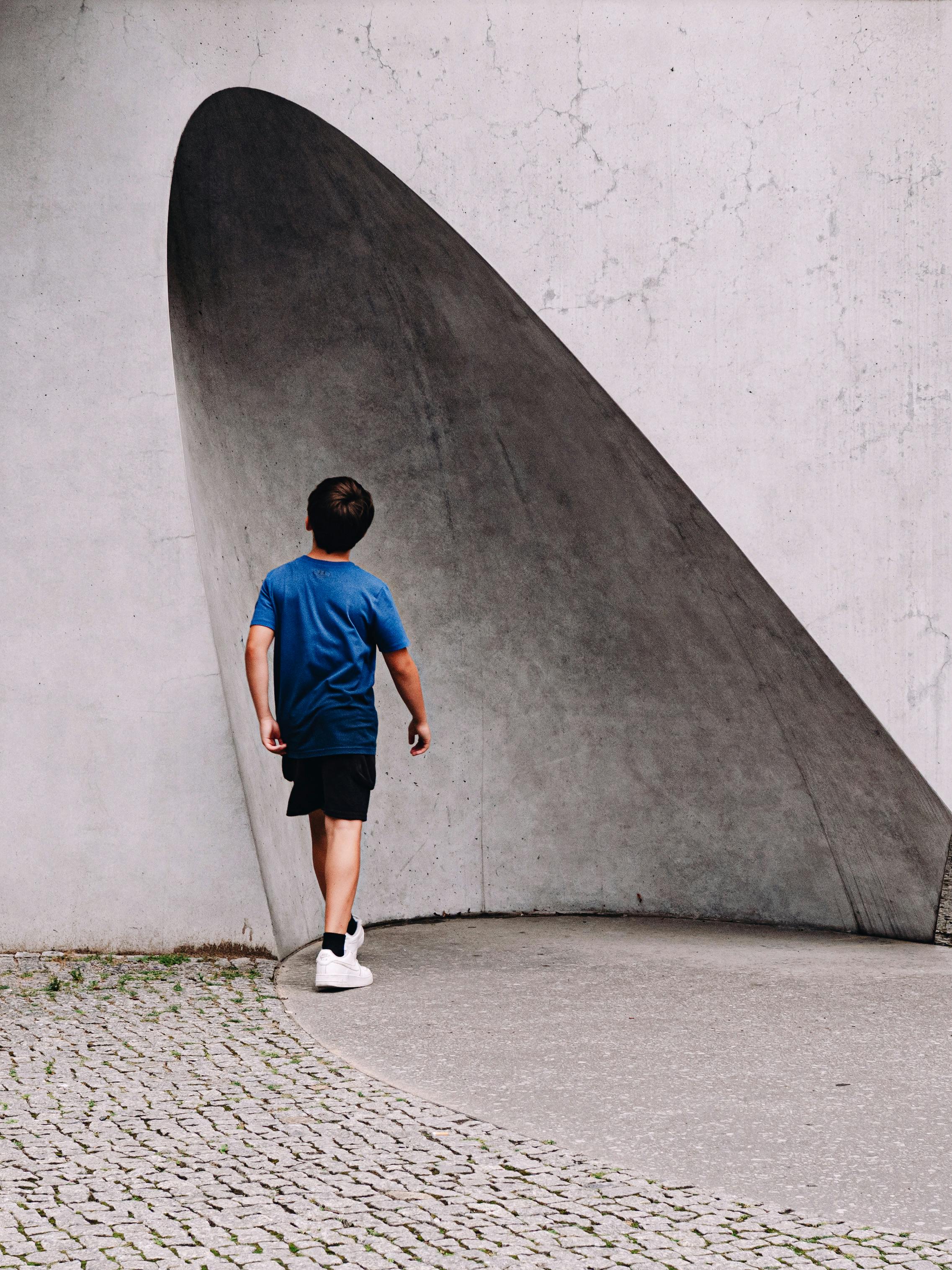 A child in a blue shirt exploring modern architectural structures in Berlin.