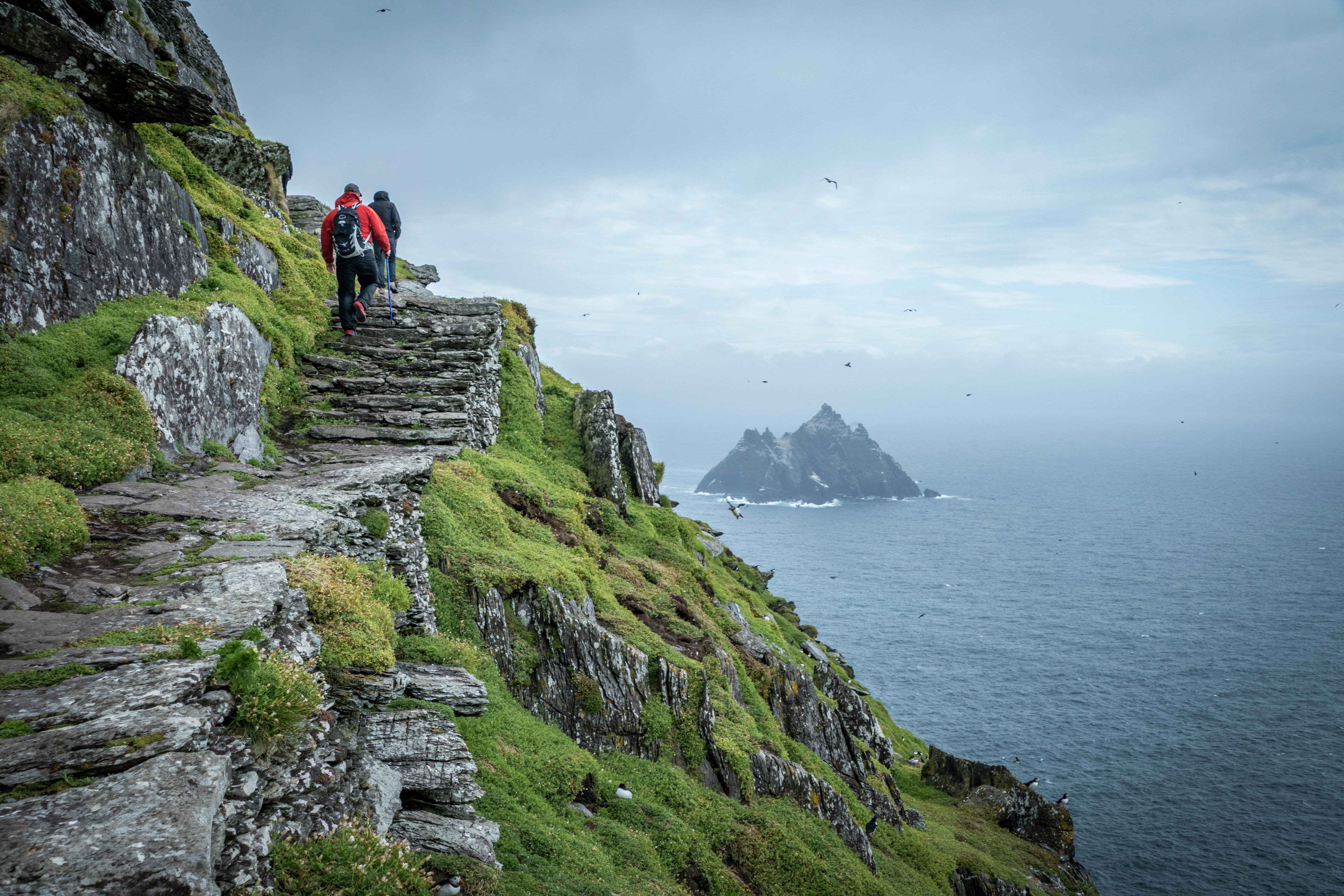 Hikers explore the rugged paths of Skellig Michael with a view of the Atlantic Ocean.