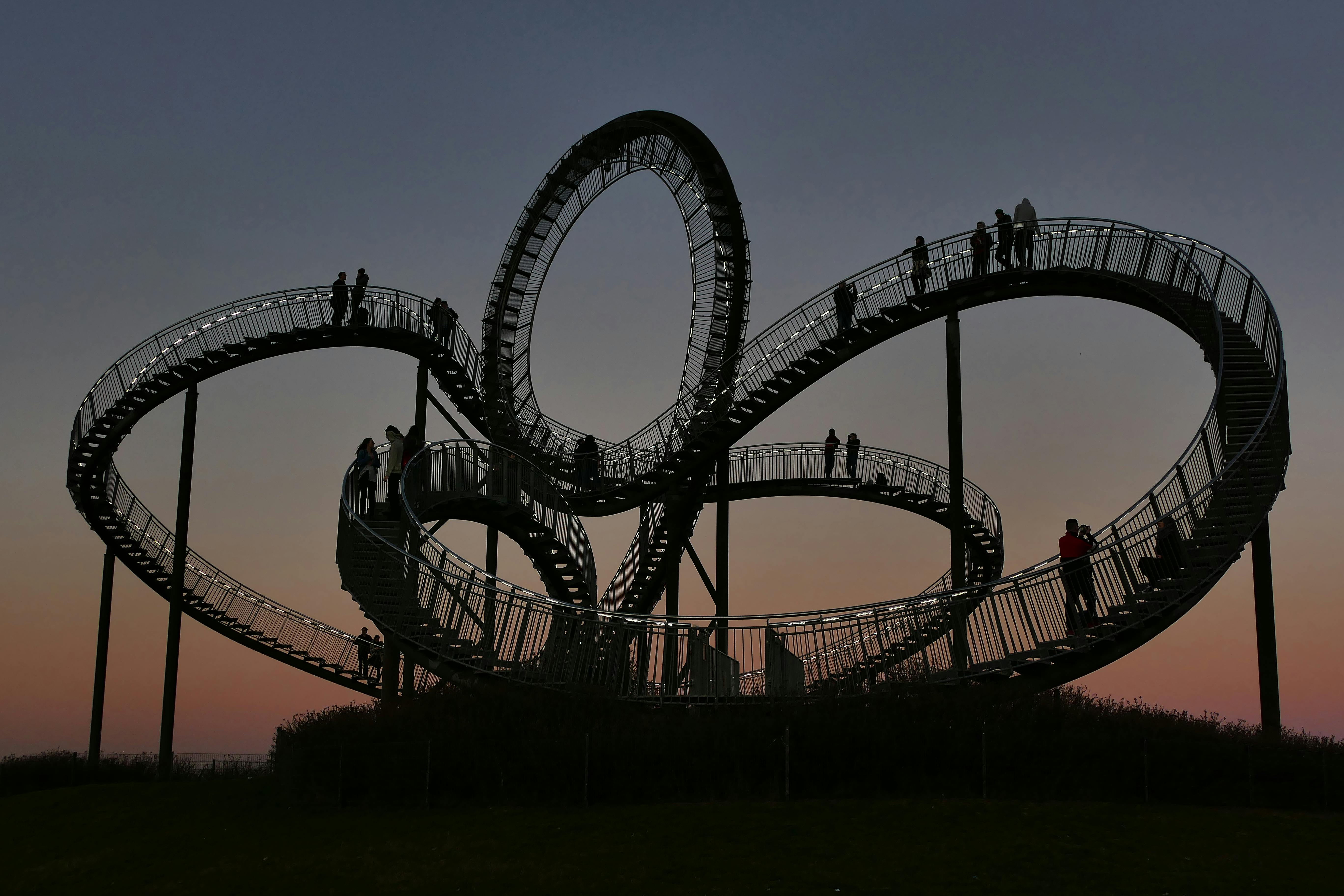 Silhouette of people walking on a spiral staircase against a mesmerizing sunset.