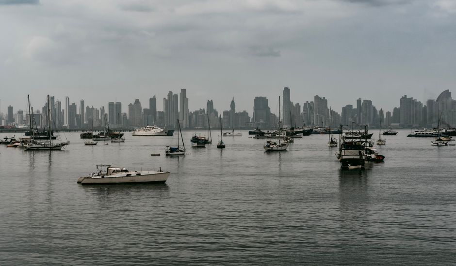 City skyline with numerous boats in Panama's harbor, creating a serene waterfront setting.