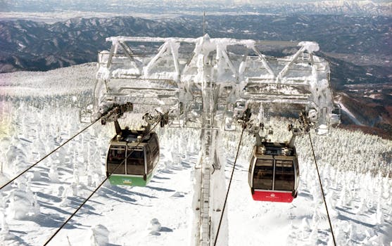 Twin gondolas traverse the snowy landscape on a mountain in Yamagata, Japan, surrounded by frosted trees.