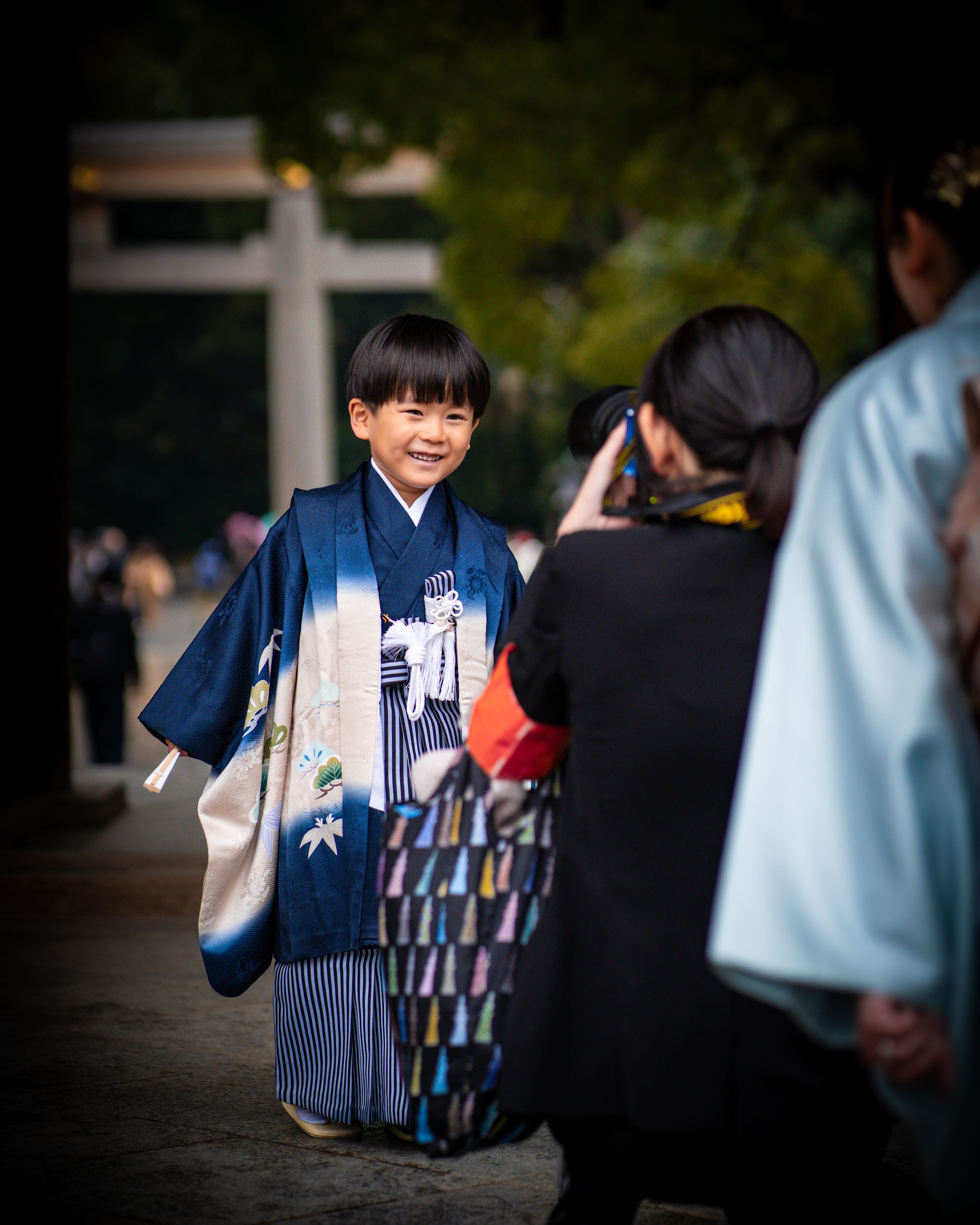 羽織袴を着た男の子が神社の境内で写真を撮ってもらっている様子