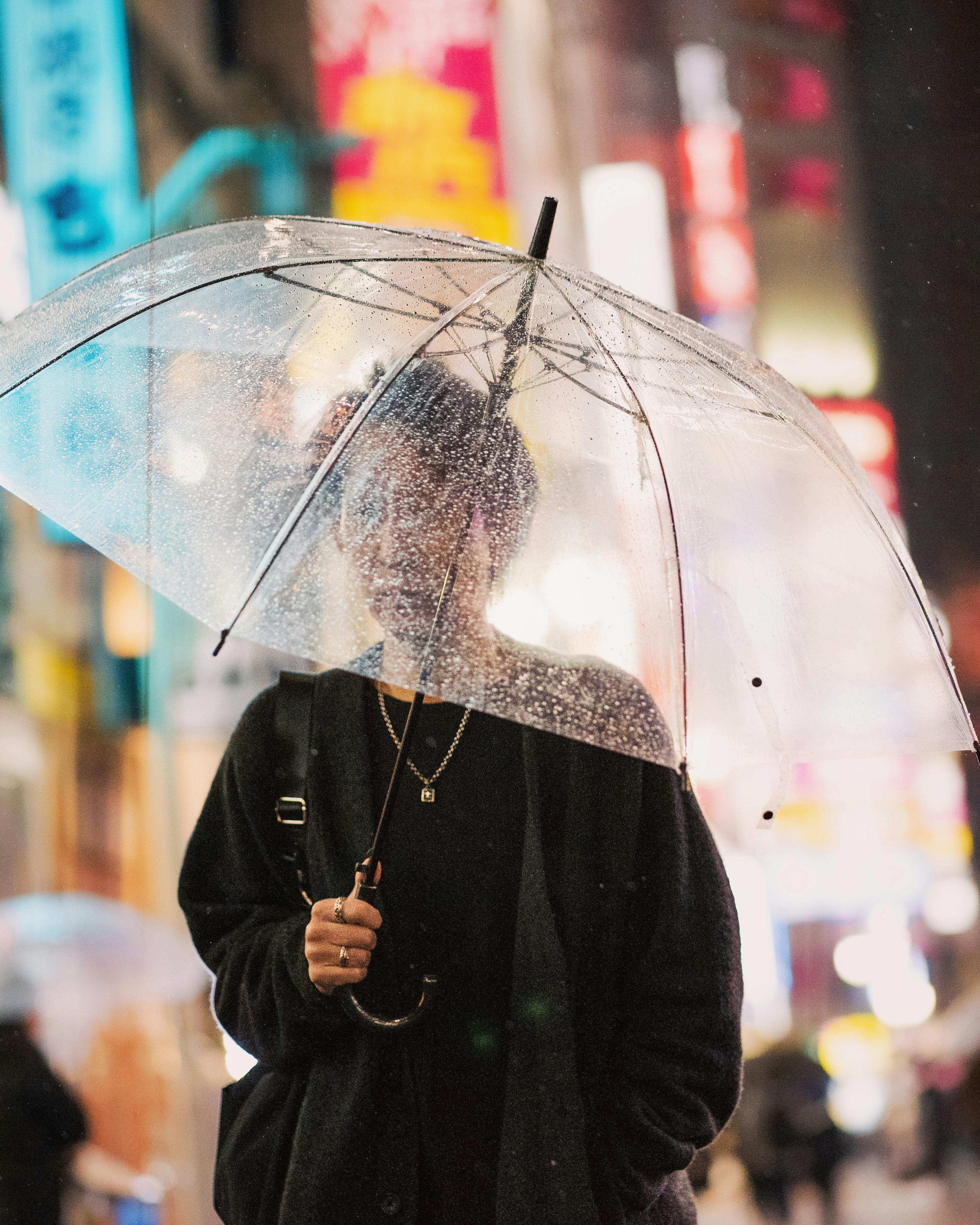 A person with an umbrella in bustling Shinjuku at night, Tokyo's vibrant cityscape.