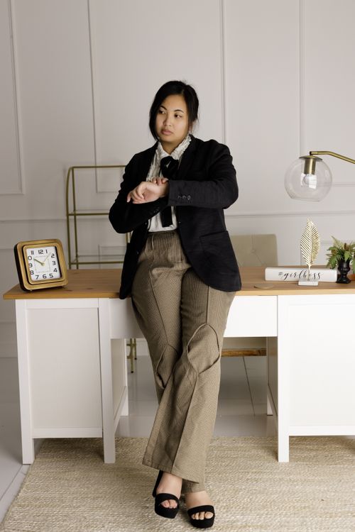 Free Professional woman looking at watch in stylish office interior, contemplating time management. Stock Photo