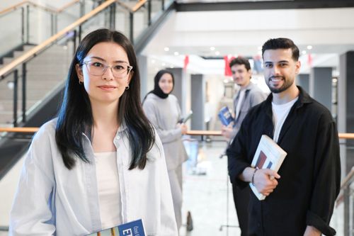 Free Group of young adults studying together in a library setting, holding books. Stock Photo