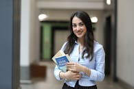 Smiling Woman Holding Books in a Hallway