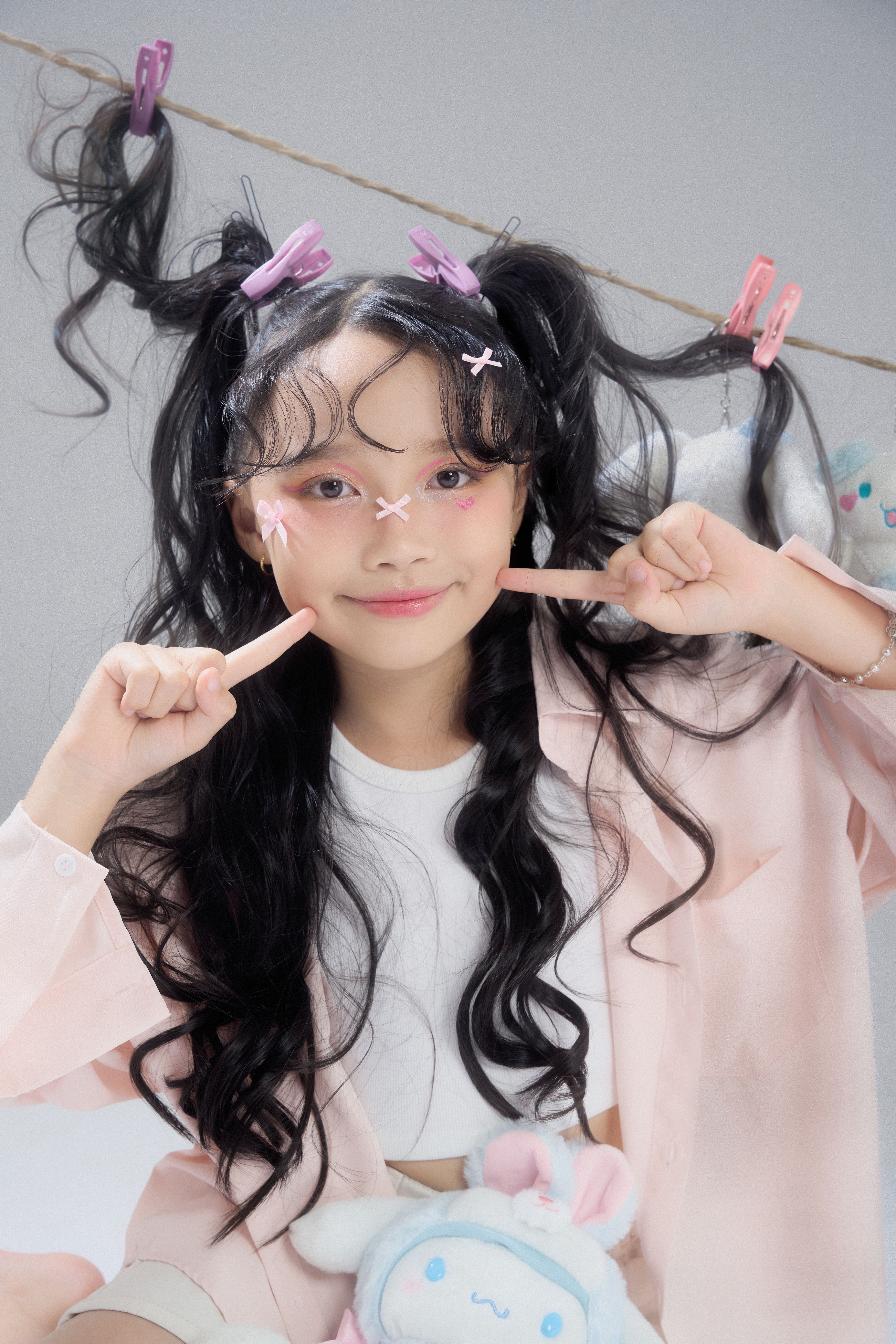 Young girl with playful hairstyle and makeup poses cheerfully indoors in Ho Chi Minh City.