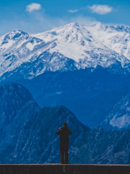 A person capturing a breathtaking snowy mountain landscape on a clear winter day.