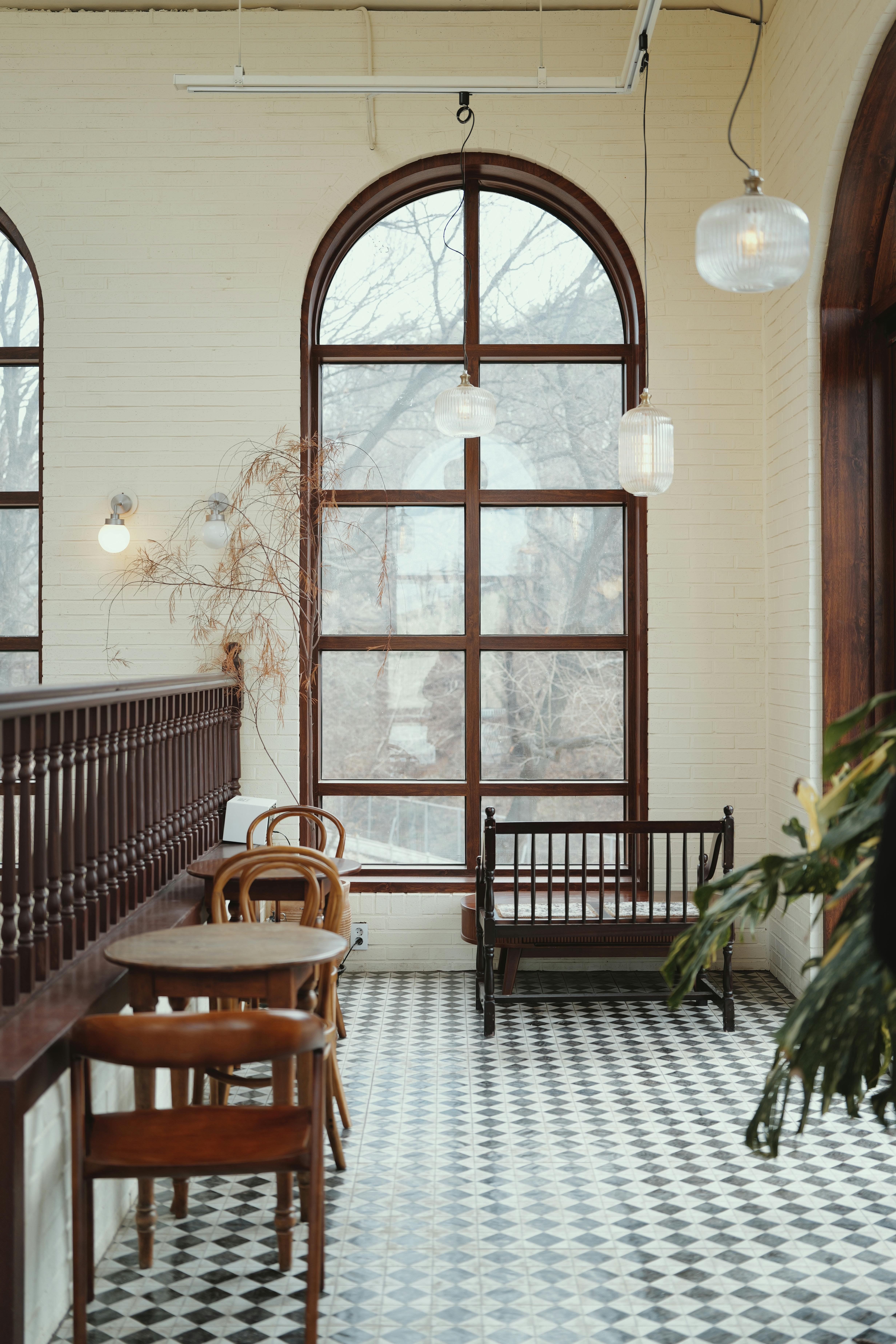 Cozy cafe interior featuring vintage design elements, a checkered floor, and large arched windows.