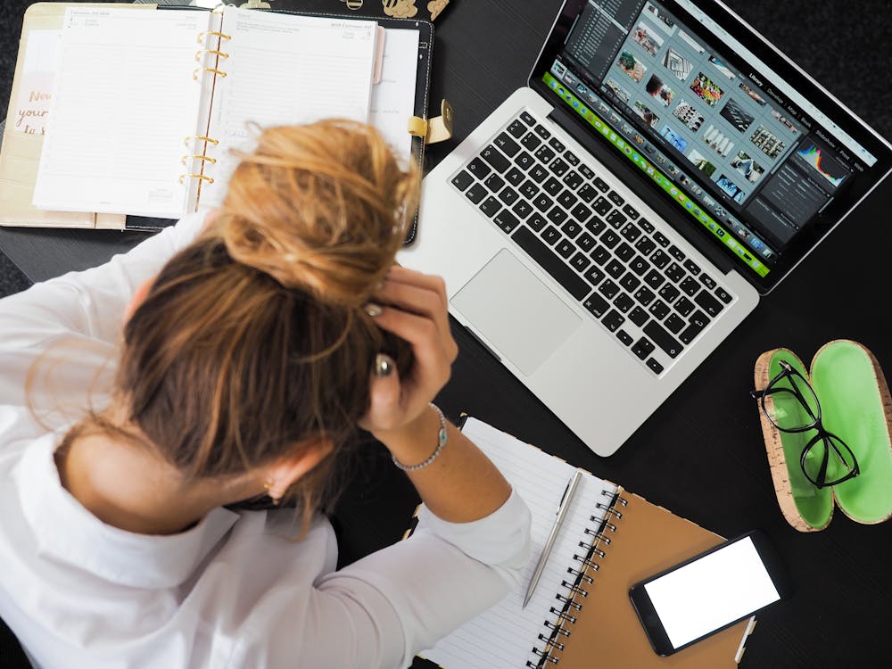 Woman Sitting in Front of Macbook and Looking Worried