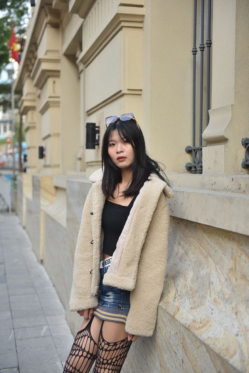 Young woman in stylish outfit posing outdoors in an urban setting.