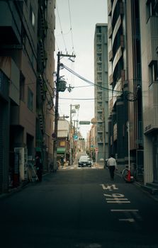 Quiet urban street in Tokyo, Japan featuring a lone pedestrian and tall buildings.