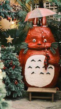 A large festive totem under a red umbrella surrounded by Christmas decorations and trees.