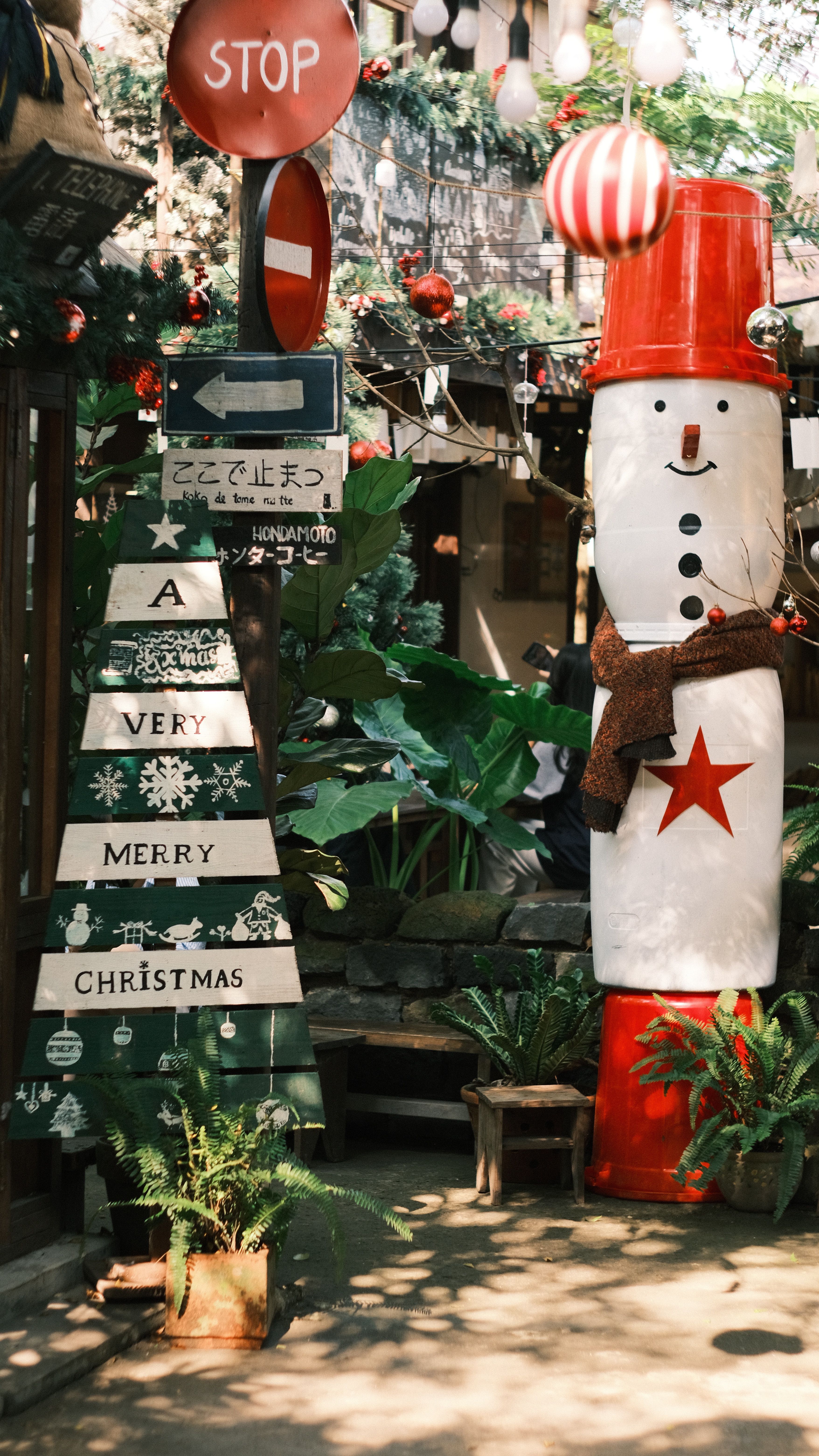 Outdoor Christmas decor with snowman and tree, conveying holiday spirit.
