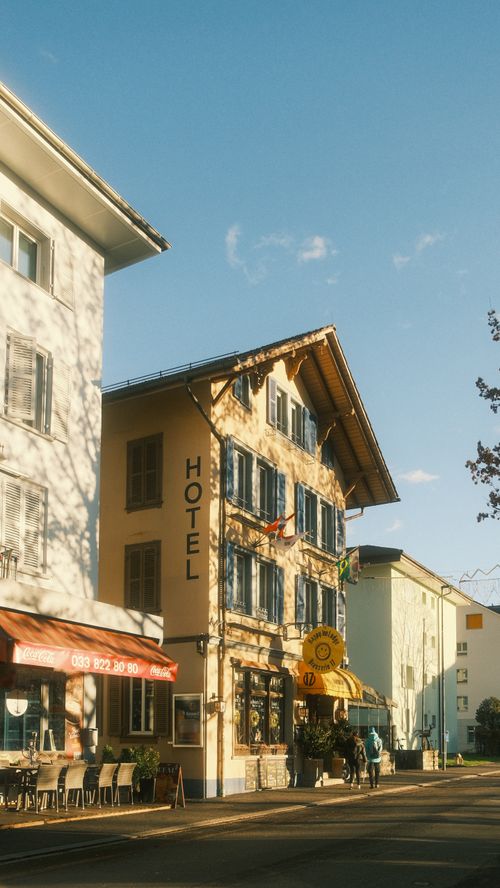 Free European street scene with sunlit hotel, vintage vibe, and pedestrians. Stock Photo