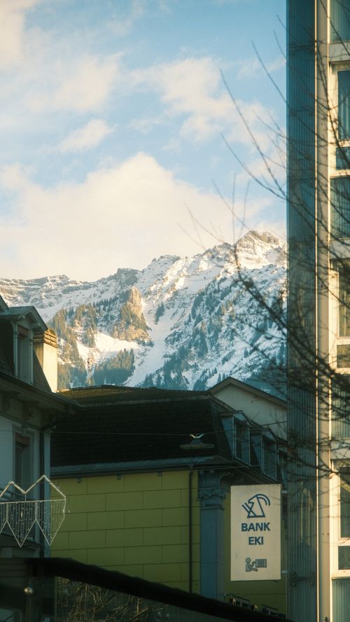 Free Snowy mountains rise behind an urban street scene with buildings. Stock Photo