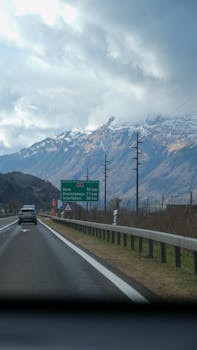 Snow-capped mountains visible from a highway in Switzerland, capturing a serene drive.