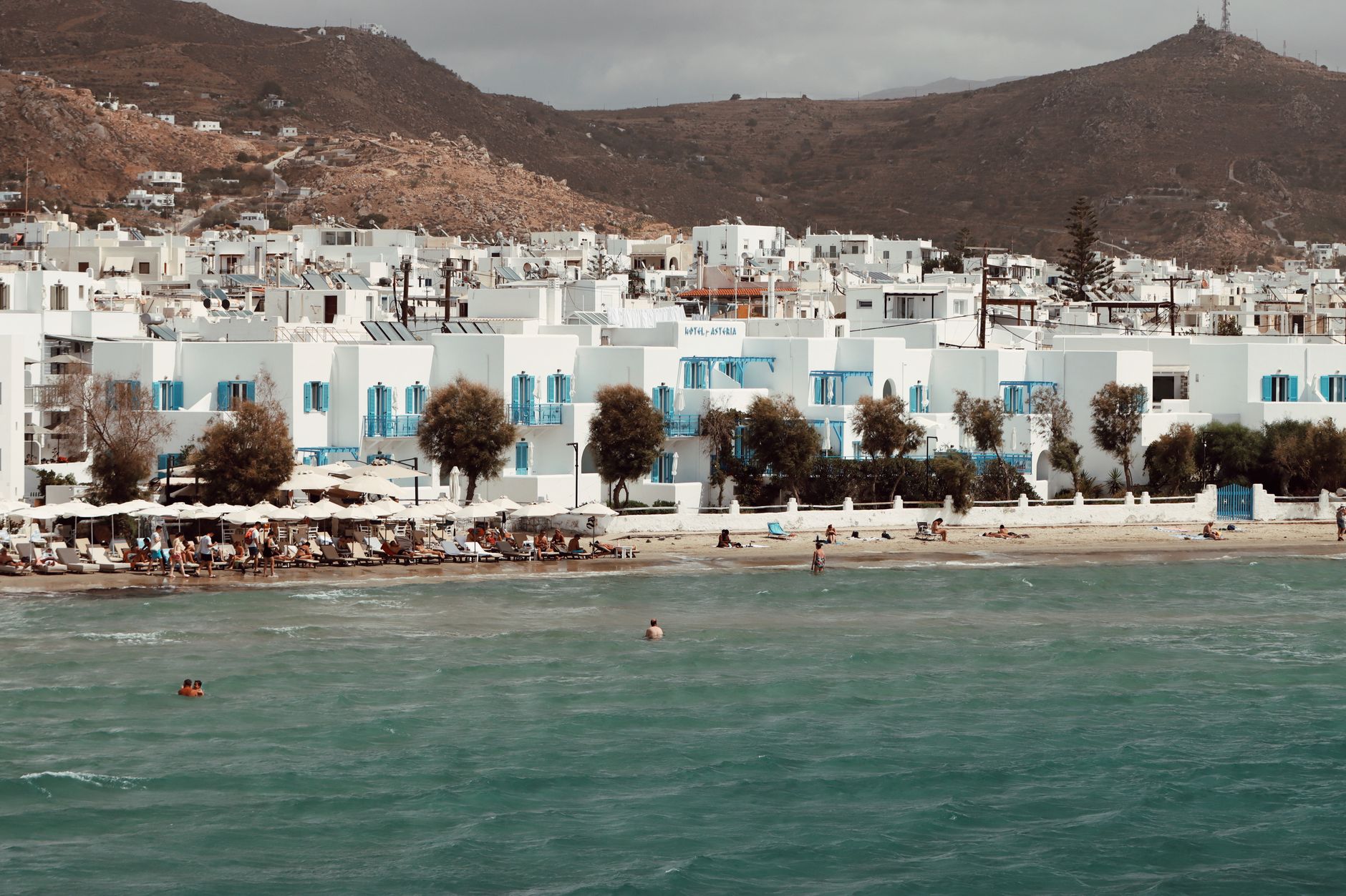 Idyllic beach scene in Naxos, Greece with charming white buildings and blue shutters.