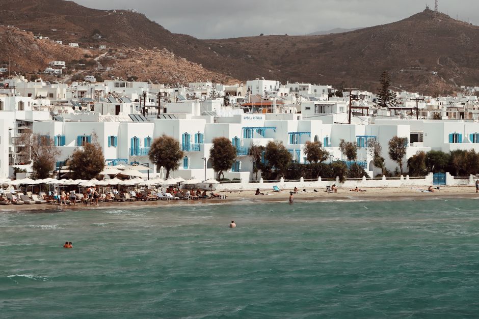 Idyllic beach scene in Naxos, Greece with charming white buildings and blue shutters.