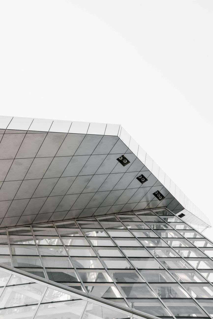 A low angle view of a modern building with glass panels and a geometric facade.
