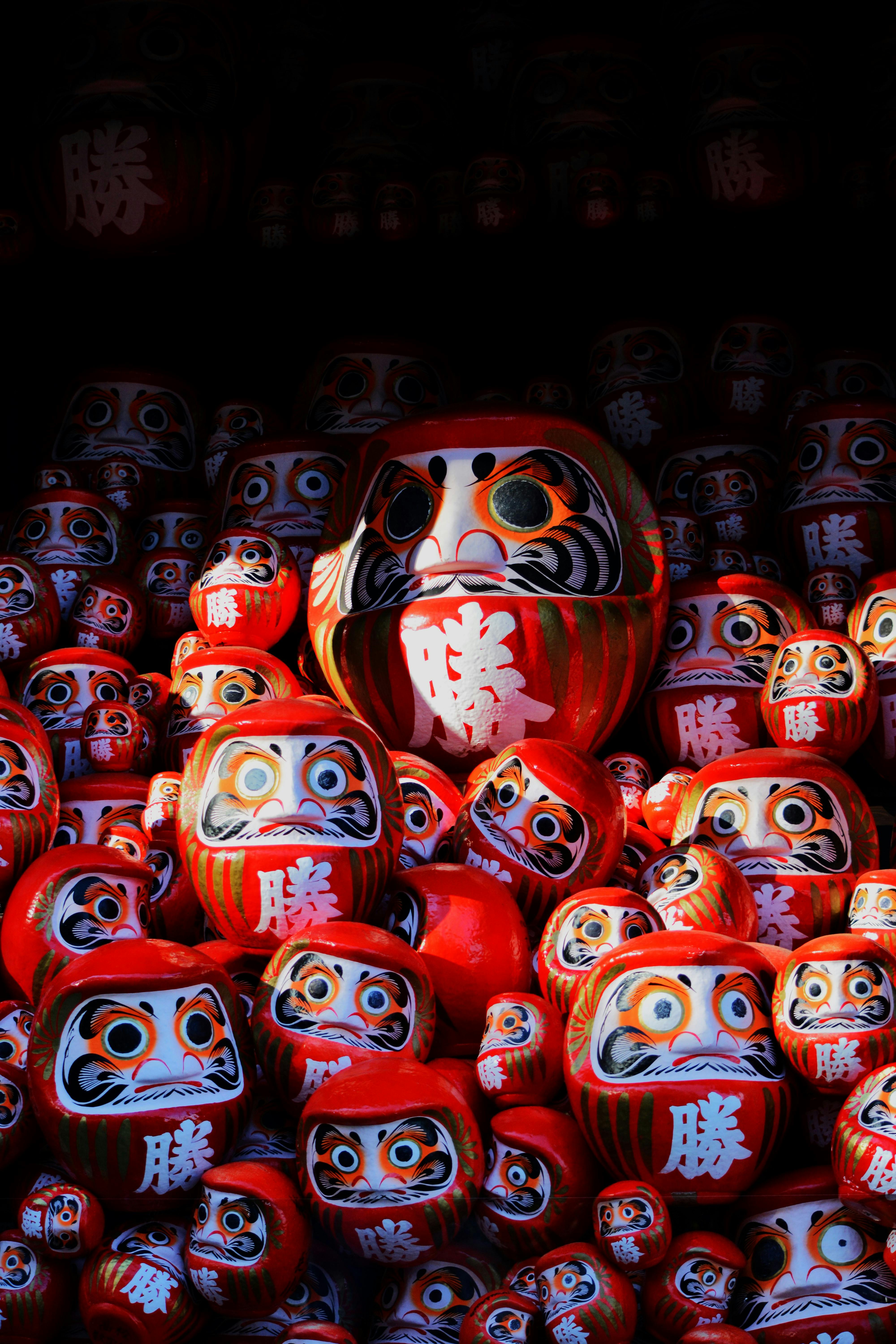 A collection of vibrant red Daruma dolls symbolizing perseverance, stacked together.