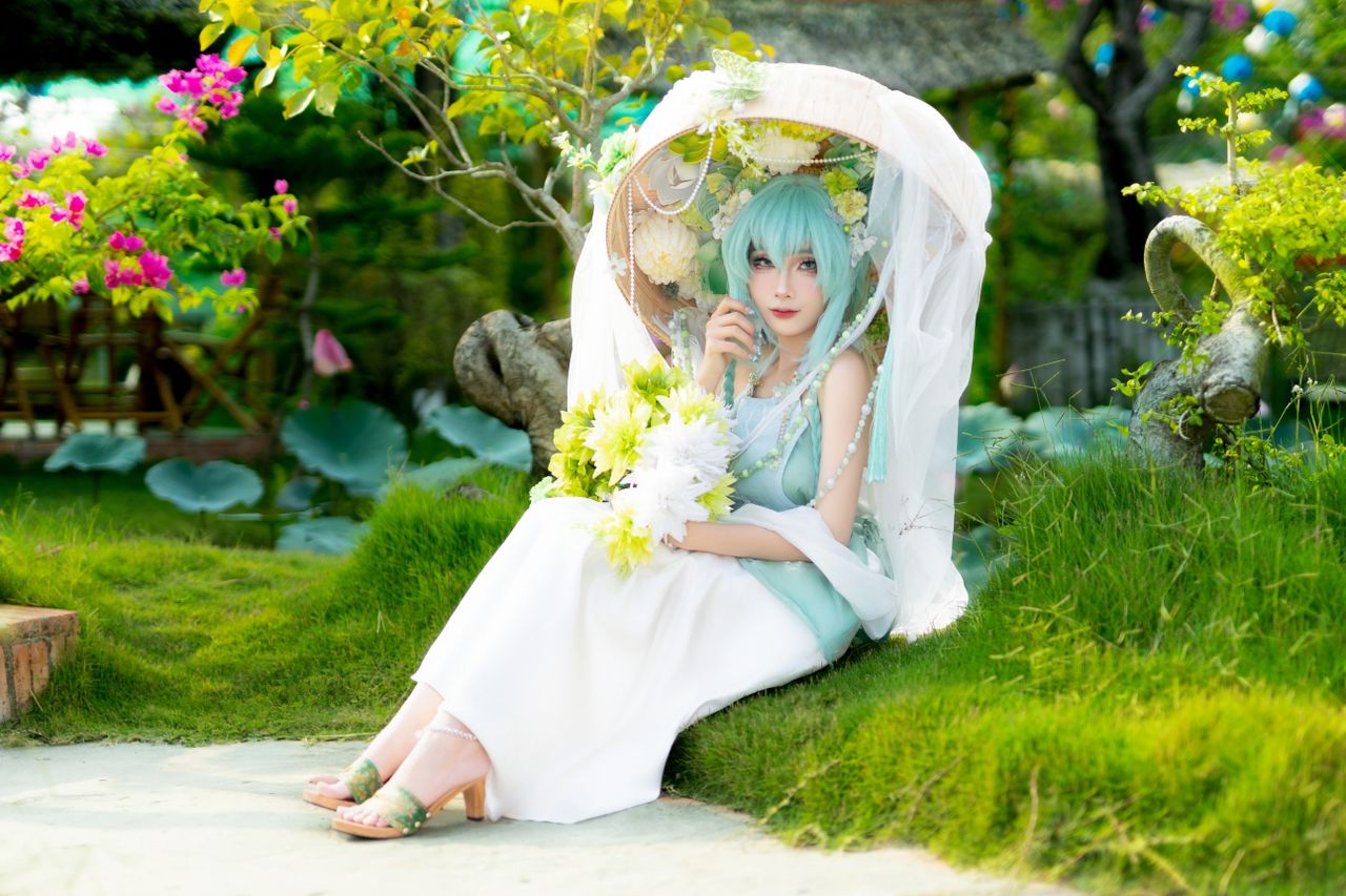 a woman in cosplay attire sits gracefully with a floral umbrella surro