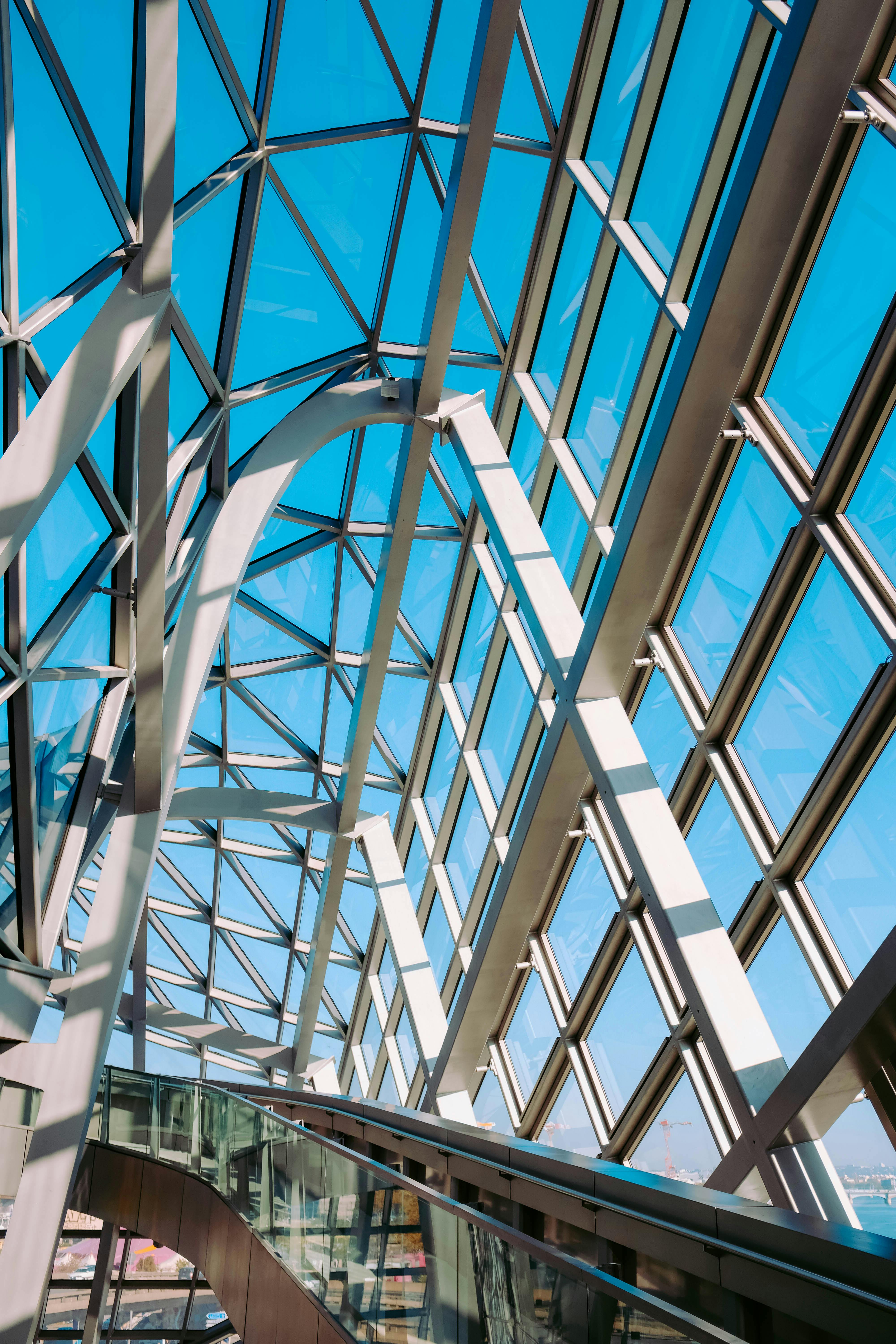 低角度视角下，现代玻璃天花板呈现几何样式，映衬着蓝天