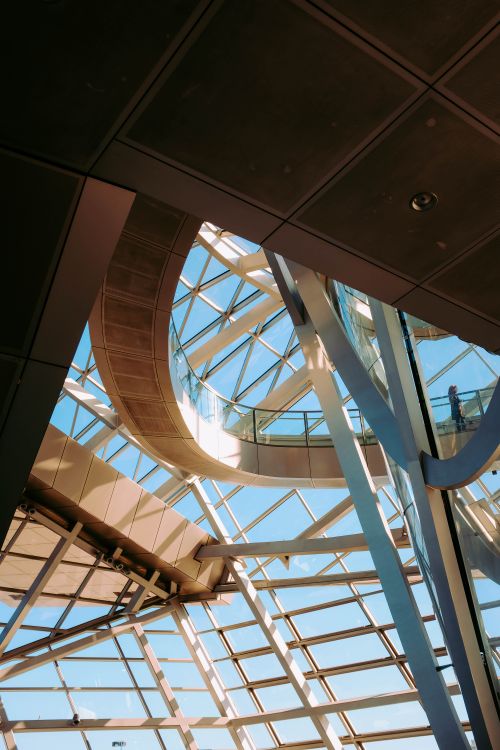 Free Low-angle view of a modern, geometric glass and steel ceiling design in an indoor space. Stock Photo