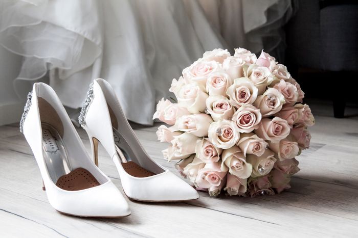 Bridal bouquet of blush roses beside wedding shoes