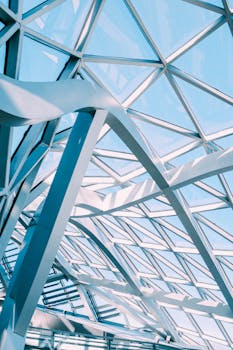现代玻璃与金属天花板的抽象视图，呈现出几何样式和阳光反射