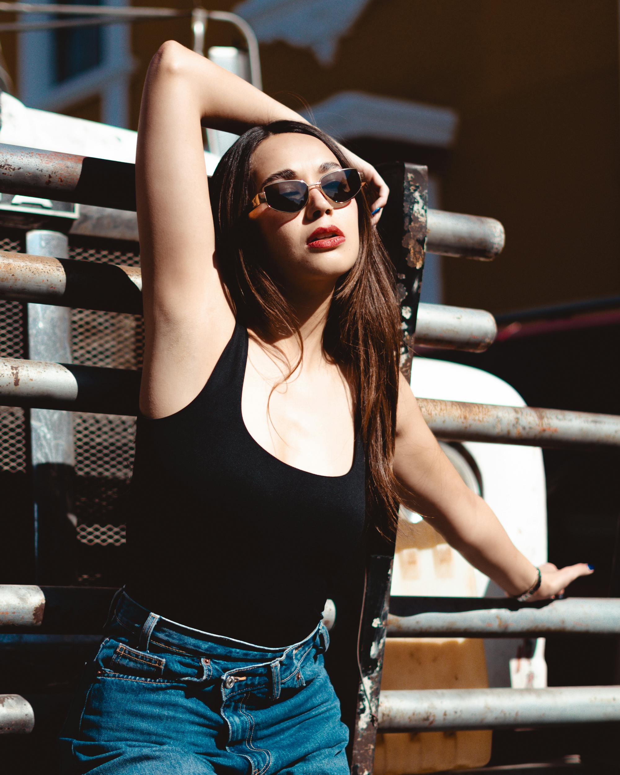 bezplatná Módní mladá žena ve slunečních brýlích sebevědomě pózuje venku a zachycuje moderní a stylovou atmosféru. Základová fotografie