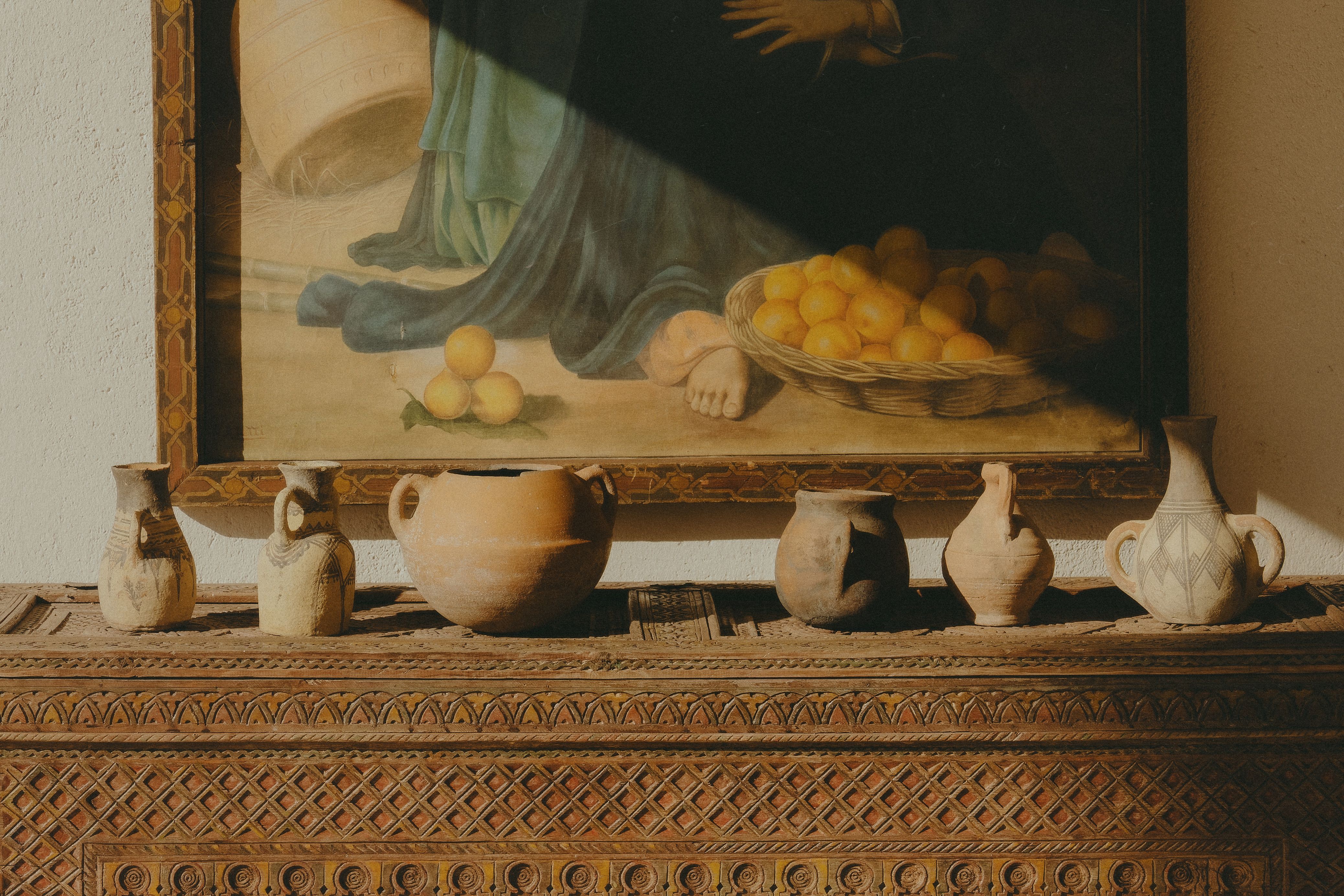 Sunlight falling on an oak dresser with brass handles, a ceramic vase of dried eucalyptus resting on top.