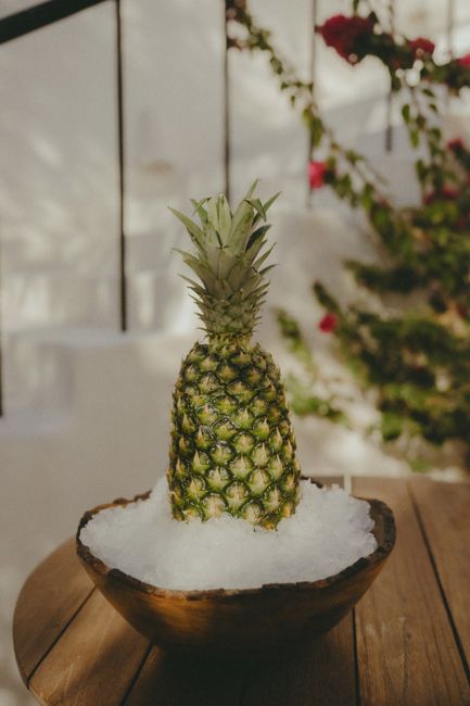 A pineapple resting on ice in a wooden bowl set in a picturesque Moroccan courtyard. A pineapple resting on ice in a wooden bowl set in a picturesque Moroccan courtyard.