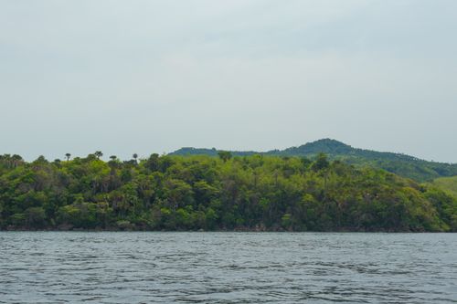 Free Tranquil image of a lush green island with surrounding water under a cloudy sky. Stock Photo