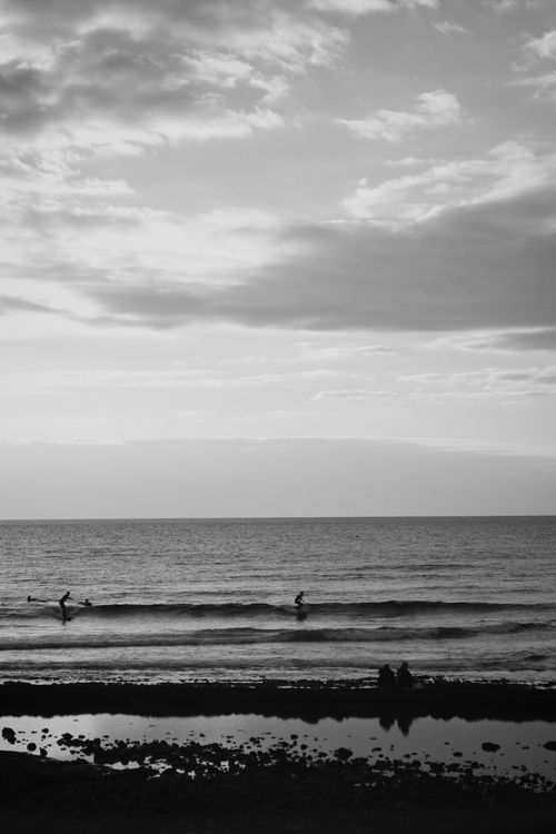 Free Captivating surfers catching waves during a serene beach sunset. Stock Photo