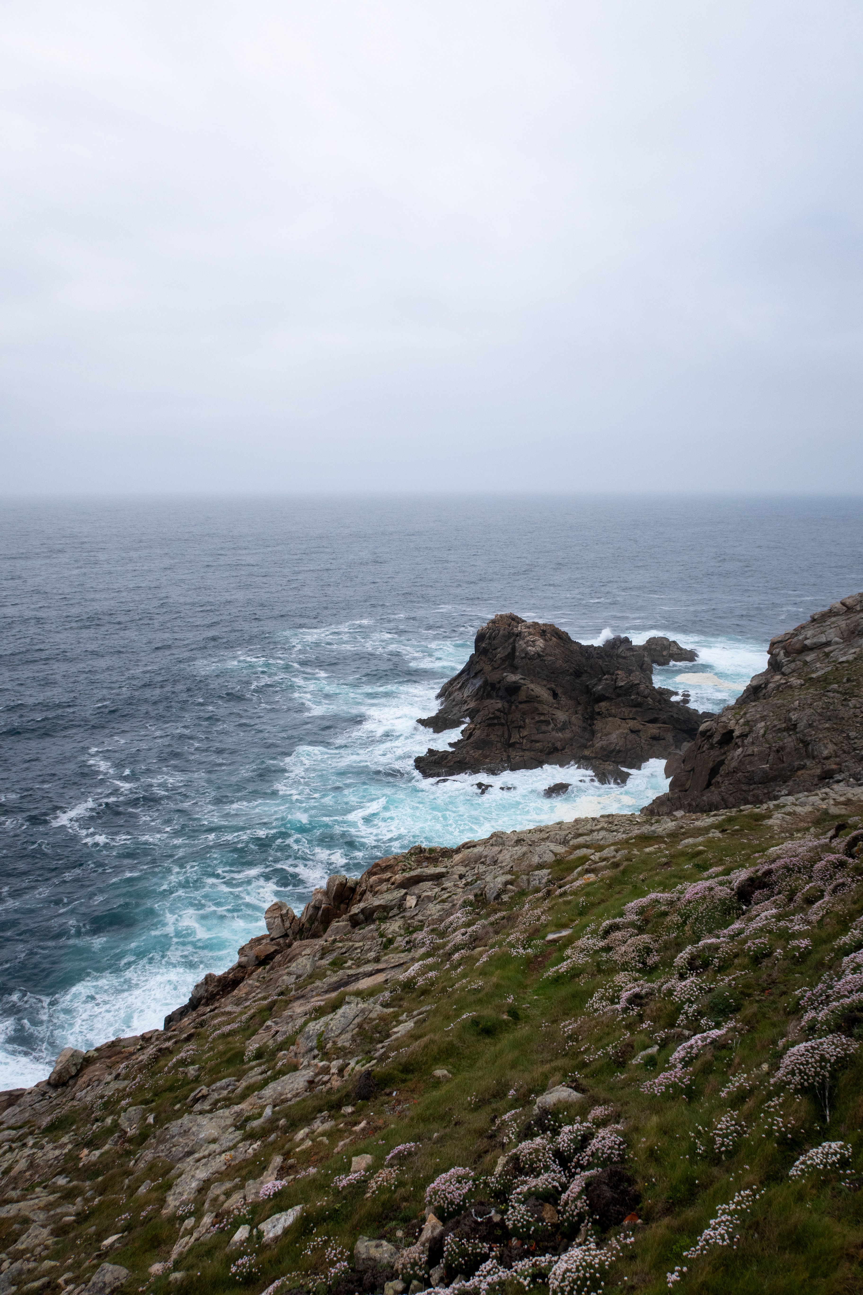 Breathtaking view of rugged cliffs and turbulent ocean waves under a cloudy sky.