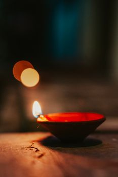 A traditional clay diya lamp illuminated during an Indian festival at night, creating a warm and inviting atmosphere.