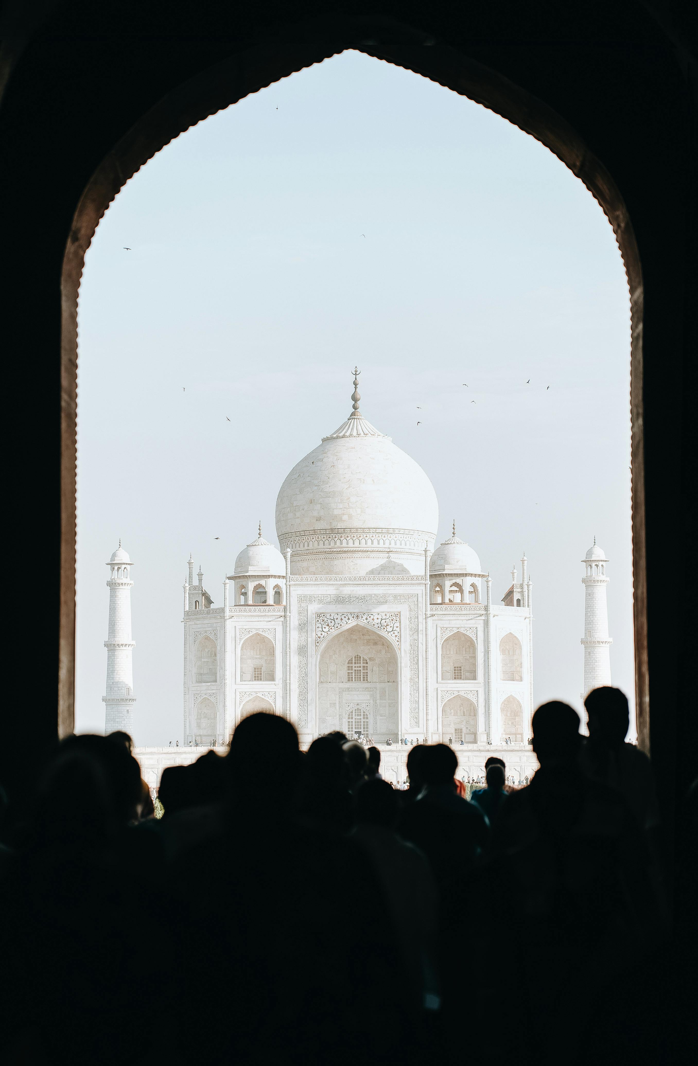 Free A large crowd views the iconic Taj Mahal in Agra, silhouetted against the bright sky. Stock Photo
