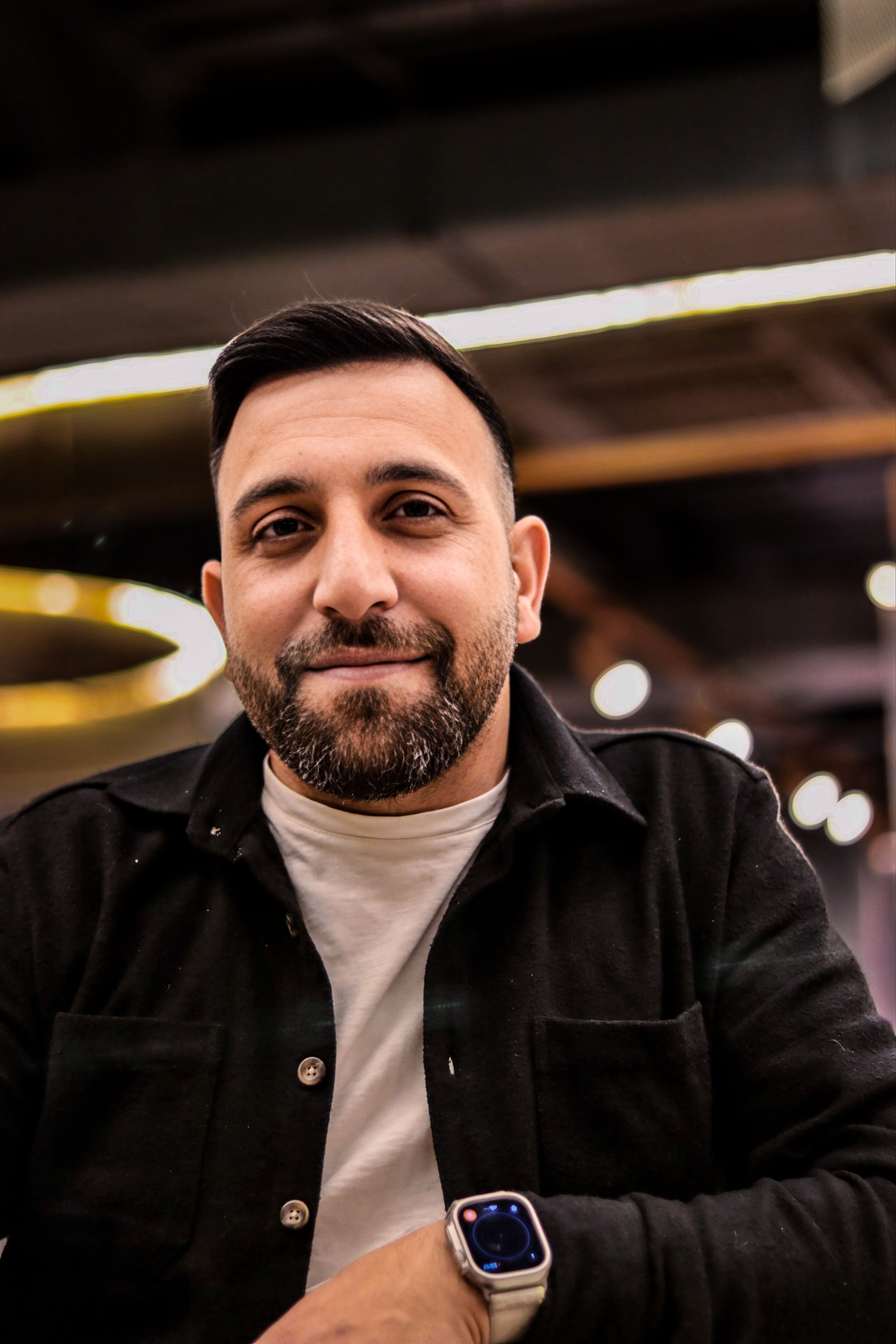 Portrait of a confident man in a cafe featuring modern interior design and ambient lighting.