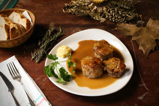 Plat de viande en sauce servi avec du pain sur une table rustique, cuisine de restaurant à Mourenx