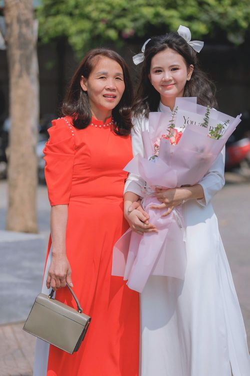 Free A mother and daughter posing with a bouquet in an outdoor setting, capturing a joyful moment. Stock Photo