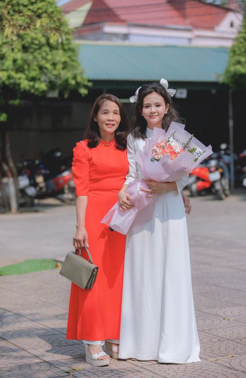 Free A joyful mother and daughter pose outdoors in traditional dresses, holding a bouquet. Stock Photo