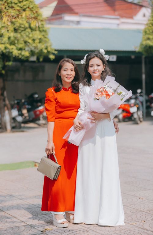 Free Two women in elegant dresses posing outdoors, holding a bouquet of flowers. Stock Photo
