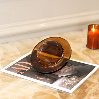 Elegant glass magnifying object on marble with a candle for stylish decor.