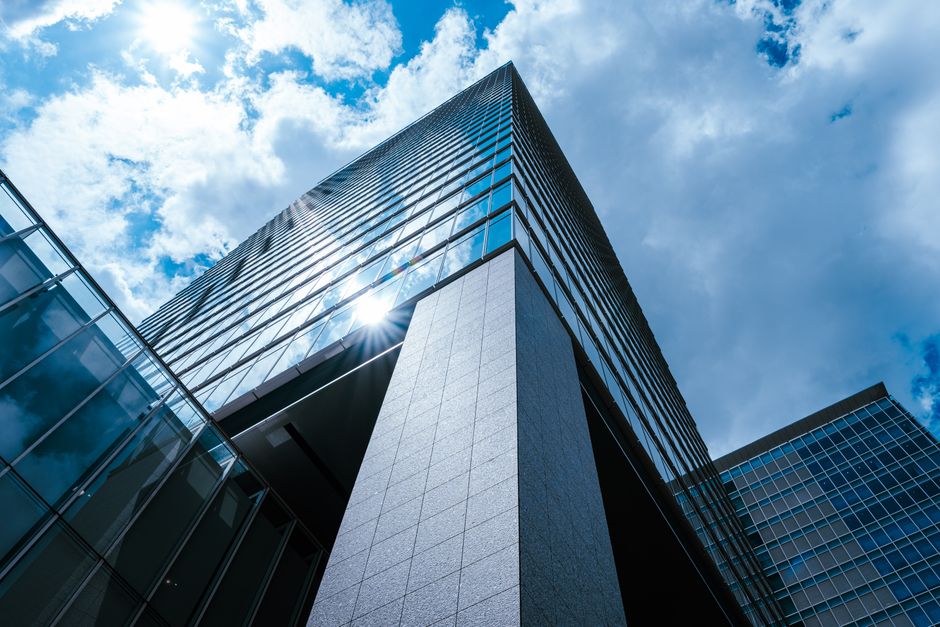 Photo by Acres of Film on Pexels A striking view of a modern skyscraper in Tokyo with sun reflecting on glass under a vibrant blue sky.