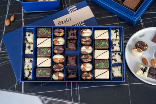 Free Discover a gourmet assortment of chocolates featuring almonds and pistachios in a stylish blue box from Kahramanmaraş. Stock Photo