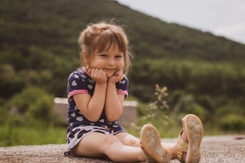 Free Adorable young girl smiling while sitting outdoors in a natural setting. Stock Photo